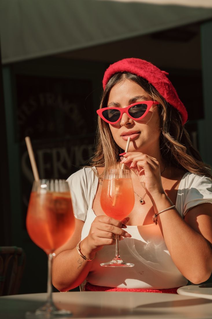 Mulher de boina vermelha com spritz em café parisiense